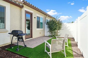 A backyard patio with a grill and two chairs